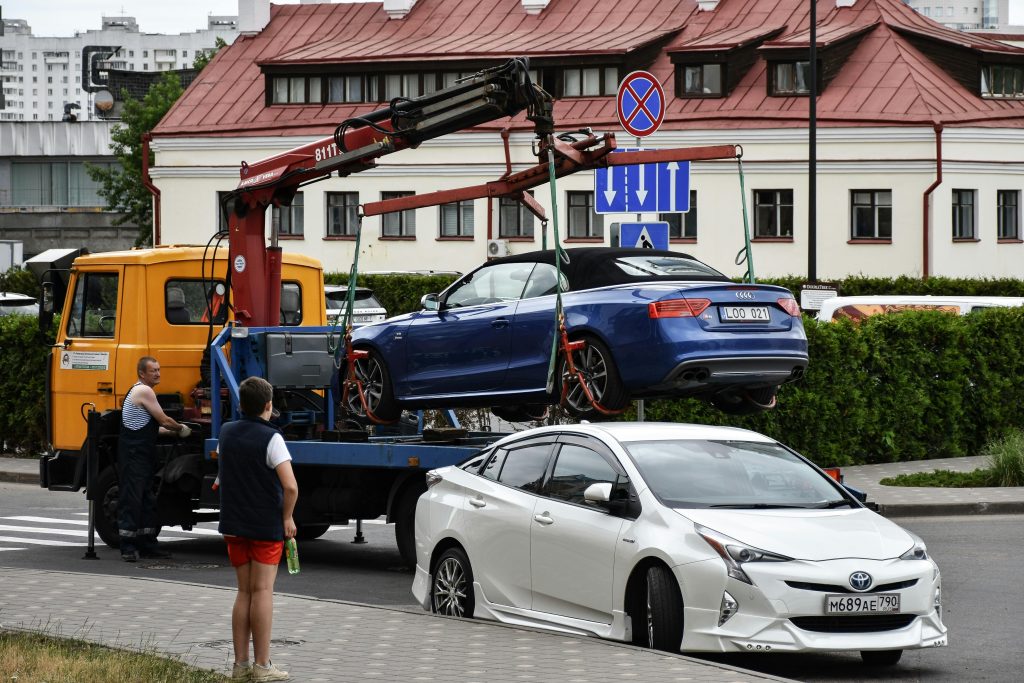 Spectehnika 4 Towing a blue Audi convertible in a bustling city street.